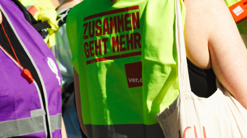 Rückansicht einer ver.di-Warnweste, auf der "Zusammen geht mehr" steht