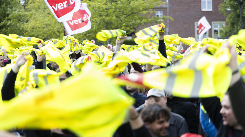Foto einer ver.di Demonstration bei dem gelbe Westen durch die Luft gewirbelt werden.