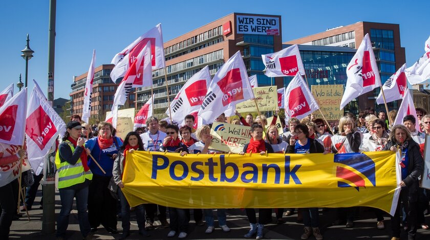 Demonstrationszug mit Postbank-Banner und ver.di-Flaggen