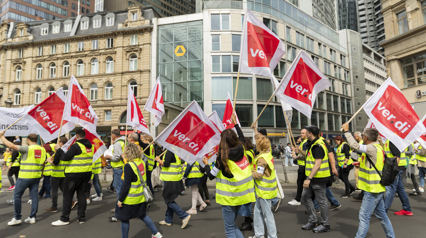 ver.di-Demonstrantenzug mit ver.di-Flaggen vor Commerzbank-Gebäude