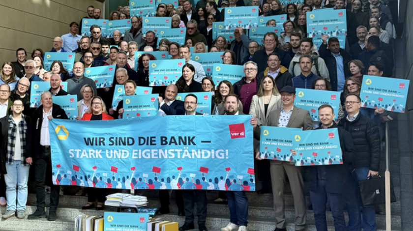 Personengruppe mit Bannern auf denen "Wir sind die Bank - stark und eigenständig" steht.