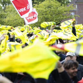 Foto einer ver.di Demonstration bei dem gelbe Westen durch die Luft gewirbelt werden.