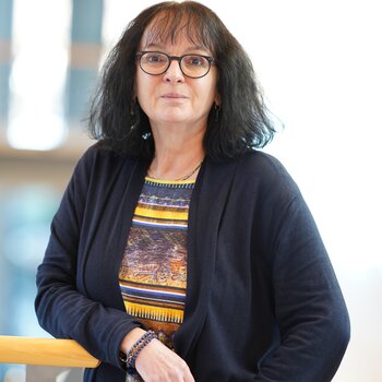 Andrea Hartmann, eine Frau mit dunklen Locken und Brille, im Portrait