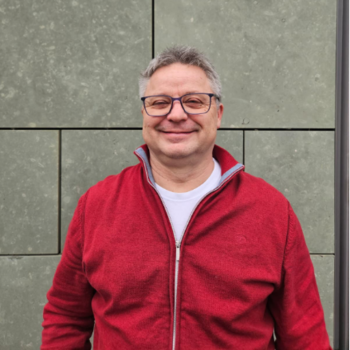 Michael Koriath ein Mann mit Brille im roten Pullover