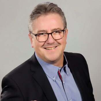 Peter Aschenbrenner, ein Mann mit Brille und Anzug